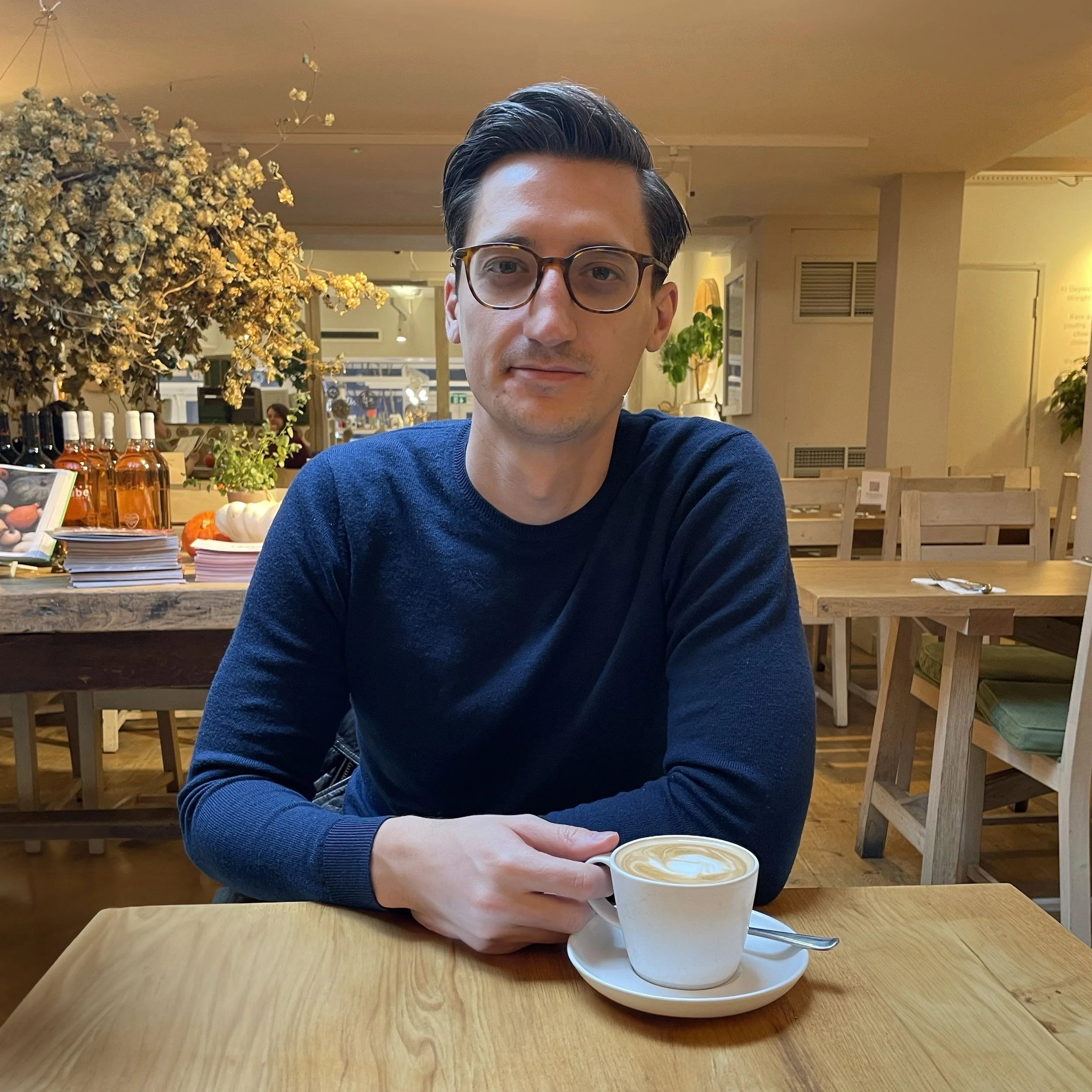 Dan Silveira seated at a cafe table with a cup of coffee